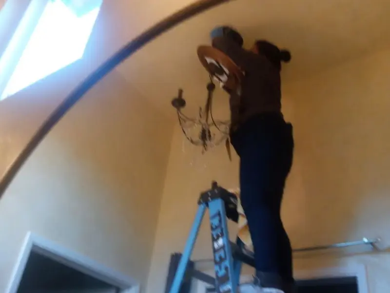 Electrician installing a chandelier in a Vestal residence
